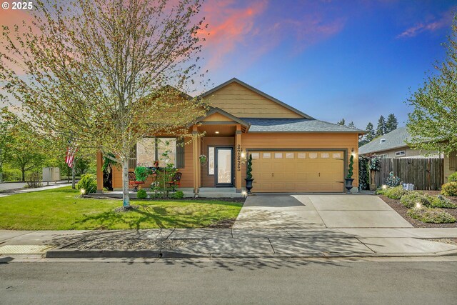 craftsman inspired home featuring a lawn, an attached garage, fence, and driveway