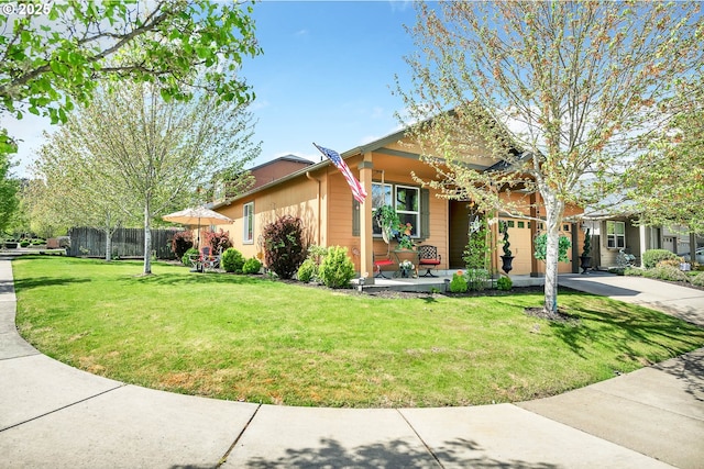 view of side of property featuring a lawn, fence, and covered porch