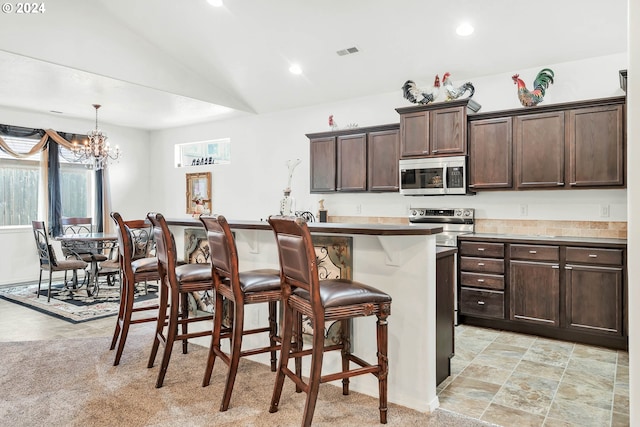 kitchen with recessed lighting, stainless steel appliances, visible vents, dark brown cabinetry, and a breakfast bar area