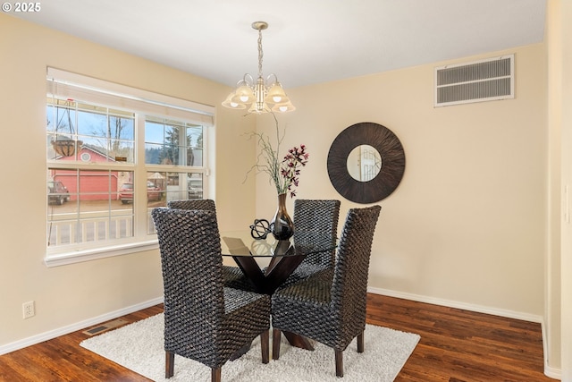 dining area with visible vents, baseboards, a notable chandelier, and wood finished floors