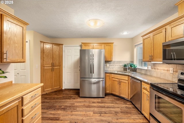 kitchen featuring dark wood-type flooring, a sink, backsplash, a textured ceiling, and stainless steel appliances