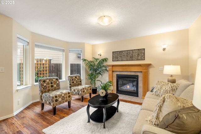 living area featuring baseboards, wood finished floors, and a tile fireplace