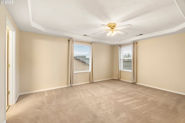 carpeted empty room featuring baseboards, a ceiling fan, and a tray ceiling