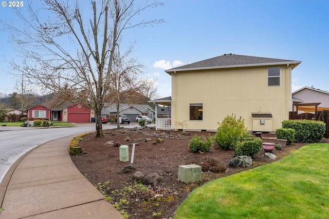 view of property exterior featuring a garage, a yard, and a shingled roof