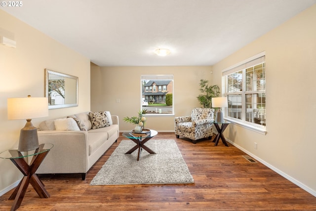 living area featuring wood finished floors, baseboards, and a healthy amount of sunlight