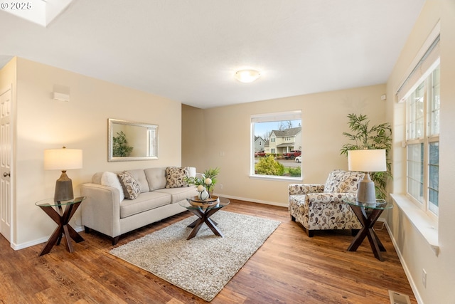 living area with visible vents, baseboards, and wood finished floors