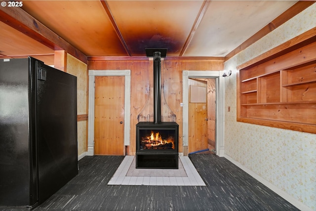 interior details featuring black refrigerator, wooden walls, and a wood stove