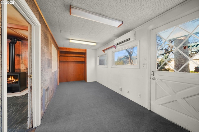 hallway featuring dark colored carpet, a wall mounted AC, and a textured ceiling