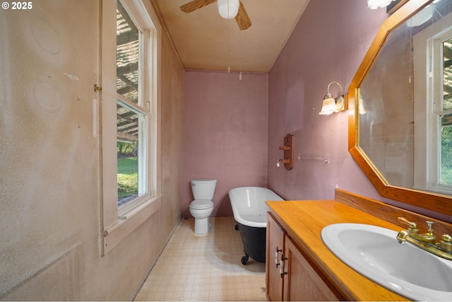 bathroom with ceiling fan, vanity, toilet, and a bathtub