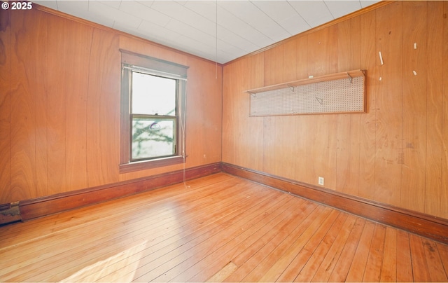 unfurnished room with wood walls and light wood-type flooring