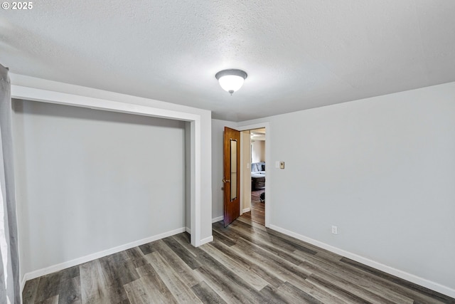 unfurnished bedroom with wood finished floors, baseboards, a closet, and a textured ceiling