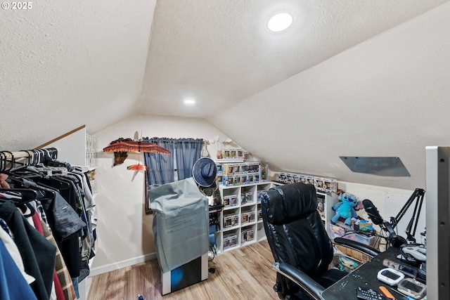 office area featuring vaulted ceiling, a textured ceiling, and wood finished floors