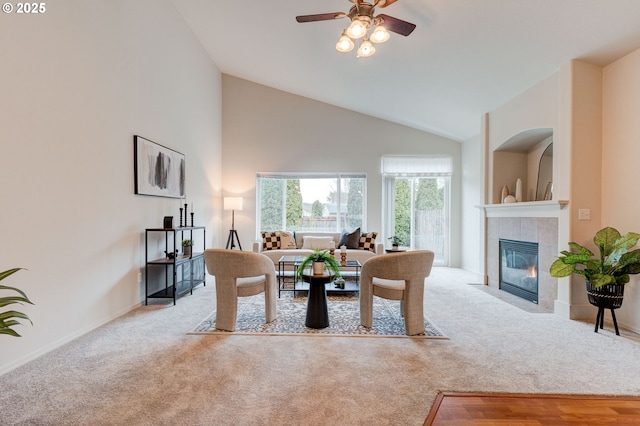 living area featuring ceiling fan, a fireplace, high vaulted ceiling, and light colored carpet