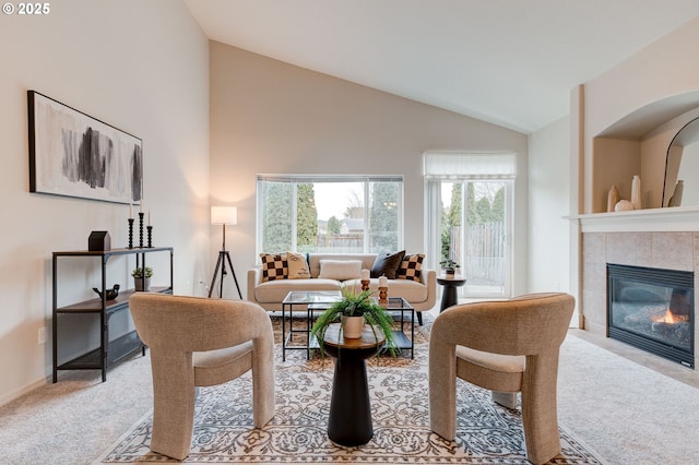 living area featuring high vaulted ceiling, baseboards, light colored carpet, and a tiled fireplace