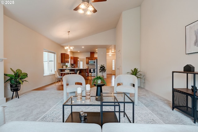 dining area with light wood-type flooring, baseboards, high vaulted ceiling, and ceiling fan with notable chandelier