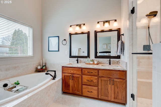 bathroom featuring a garden tub, double vanity, a stall shower, and a sink