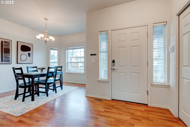 entryway featuring visible vents, a notable chandelier, light wood-style flooring, and baseboards