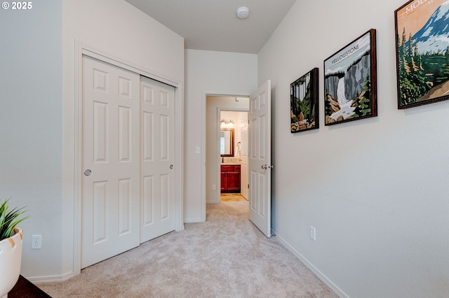 bedroom featuring a closet, light carpet, and baseboards