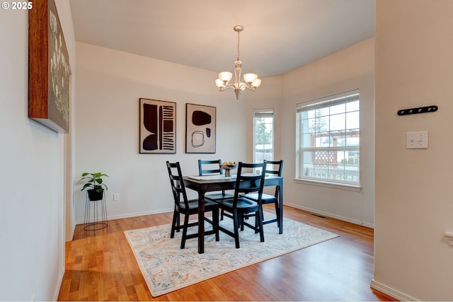 dining space featuring light wood-style flooring, visible vents, baseboards, and a notable chandelier