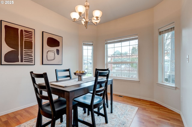 dining room with a notable chandelier, light wood-type flooring, visible vents, and baseboards