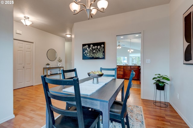 dining area featuring light wood-style floors, a notable chandelier, and baseboards