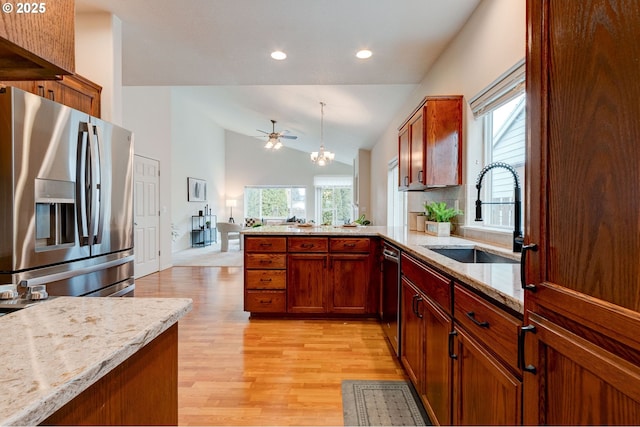 kitchen with brown cabinets, stainless steel appliances, vaulted ceiling, a sink, and light stone countertops