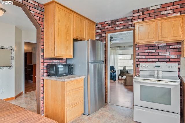 kitchen featuring ceiling fan, light tile patterned floors, stainless steel fridge, and white range with electric stovetop