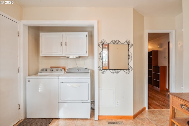 laundry area with cabinets, light tile patterned floors, and washing machine and clothes dryer