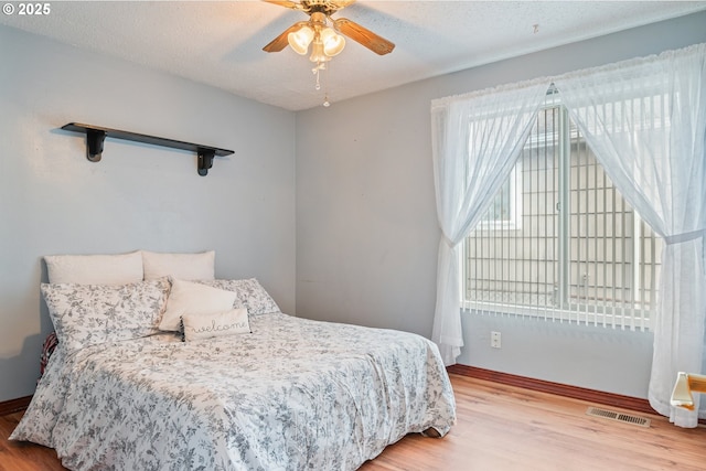 bedroom with ceiling fan, a textured ceiling, and light hardwood / wood-style flooring