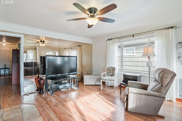 living room with ceiling fan, light hardwood / wood-style floors, and a textured ceiling