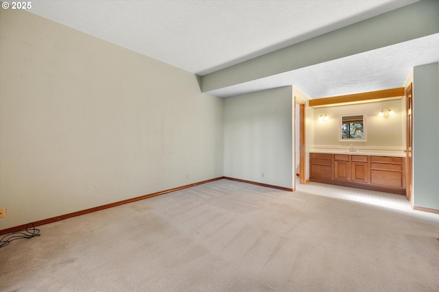 unfurnished bedroom with light carpet, baseboards, a textured ceiling, and ensuite bathroom