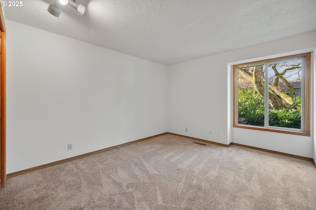 unfurnished room featuring light colored carpet, a textured ceiling, and baseboards