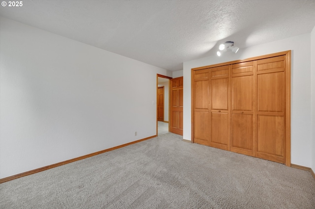 unfurnished bedroom featuring a textured ceiling, carpet flooring, and baseboards