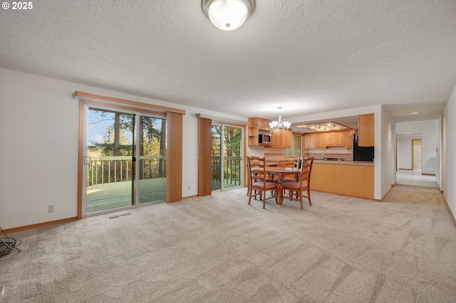 dining space featuring light carpet, a textured ceiling, baseboards, and an inviting chandelier