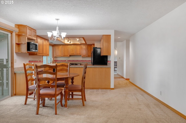 kitchen featuring a chandelier, freestanding refrigerator, stainless steel microwave, and light carpet