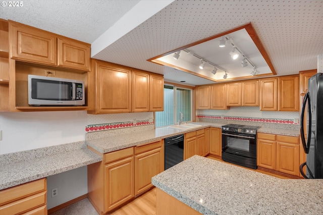 kitchen featuring built in desk, light wood finished floors, a sink, a peninsula, and black appliances