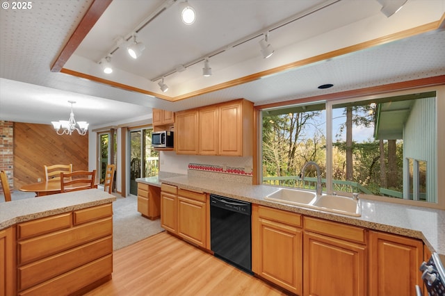 kitchen with light wood-style flooring, wood walls, a sink, dishwasher, and stainless steel microwave