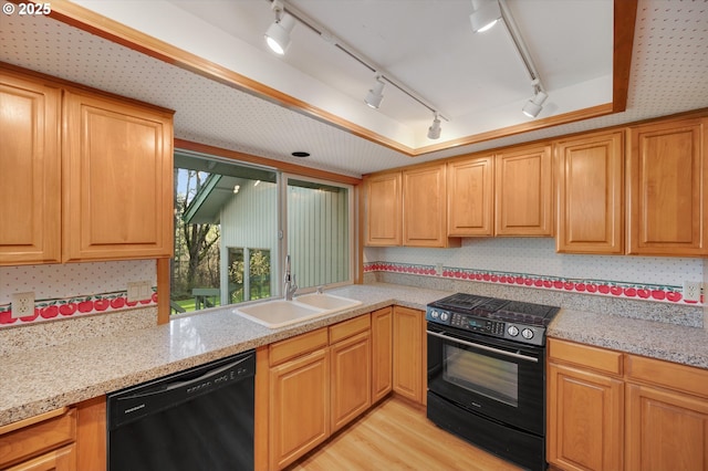 kitchen featuring rail lighting, light wood-style flooring, a sink, light stone countertops, and black appliances