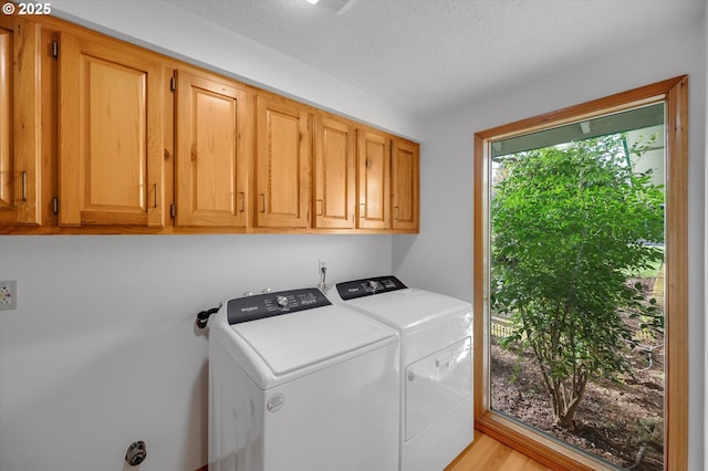 clothes washing area with washing machine and dryer, cabinet space, and a textured ceiling