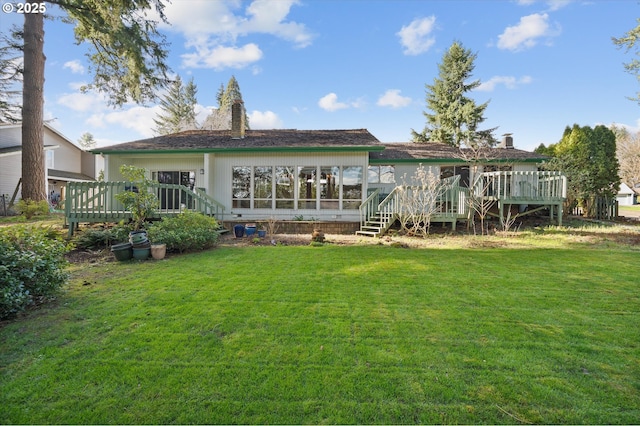 back of property with a deck, a yard, and a chimney