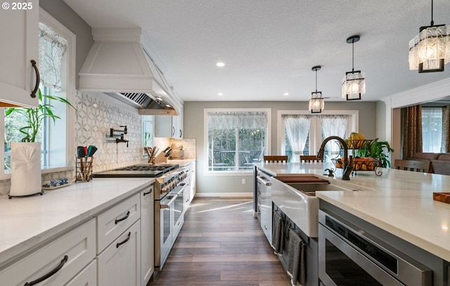 kitchen featuring stainless steel appliances, premium range hood, dark wood-type flooring, white cabinets, and backsplash