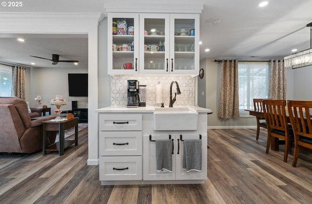 bar with dark wood-style floors, backsplash, a sink, and baseboards