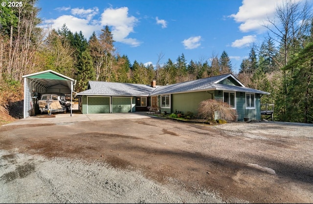 view of front of property with a garage, concrete driveway, a carport, and a chimney