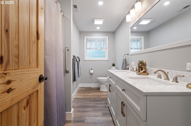 full bath with toilet, a sink, and visible vents