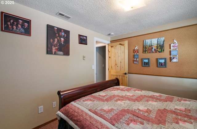 bedroom with visible vents, a textured ceiling, and carpet flooring