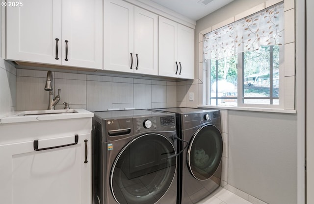 clothes washing area featuring cabinet space, visible vents, a sink, and independent washer and dryer