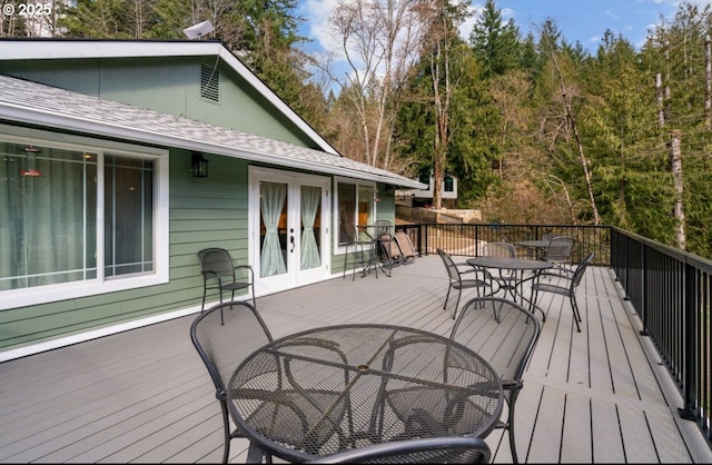 wooden terrace with outdoor dining area and french doors