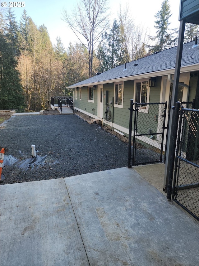 view of front of house featuring a shingled roof, a gate, driveway, and fence