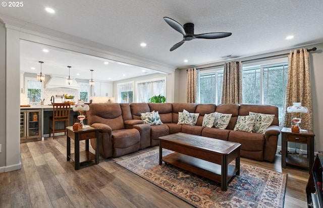 living room with beverage cooler, ceiling fan, a textured ceiling, and wood finished floors