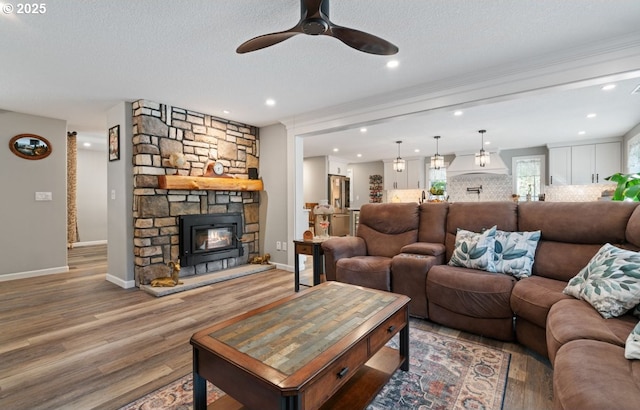 living room with a textured ceiling, recessed lighting, a fireplace, wood finished floors, and baseboards